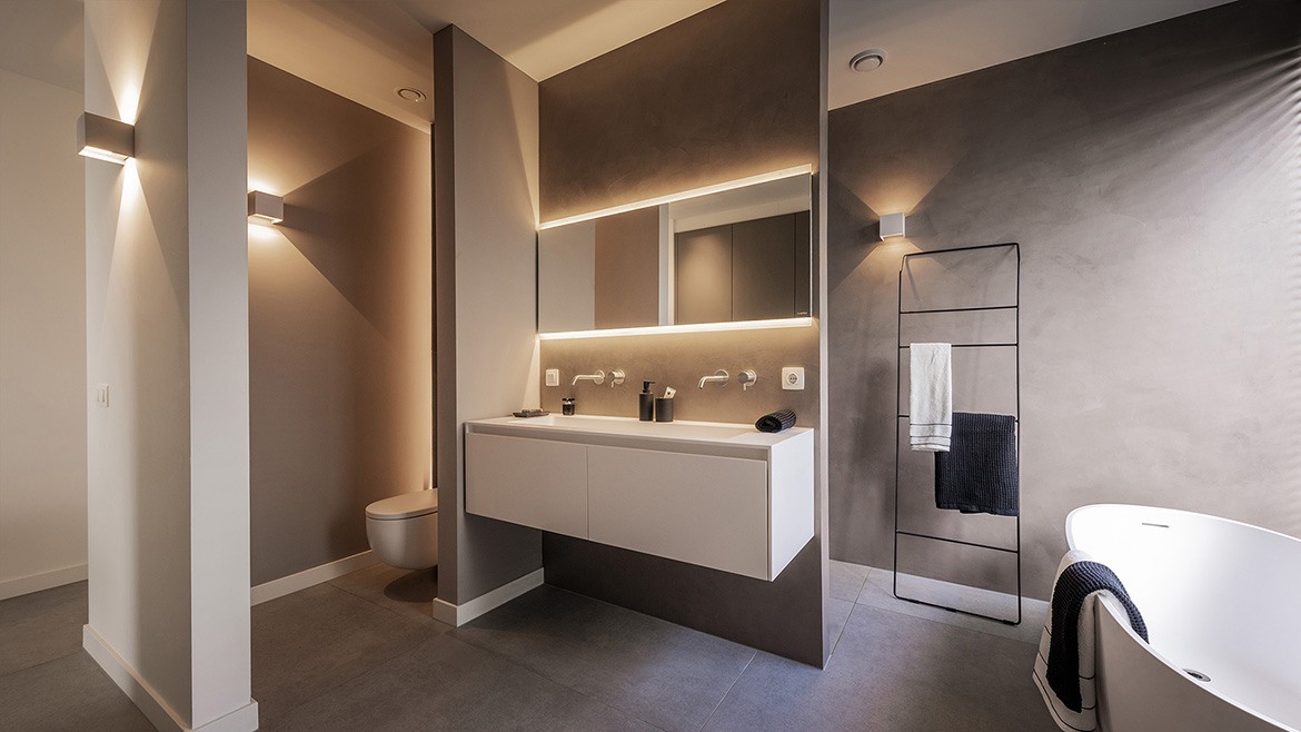 Luxe badkamer. Minimalistisch design badkamer van B Dutch. Luxe badkamer. Minimalistisch design badkamer van B Dutch. Voorzien van B Dutch ligbad Evolution van mat wit solid surface Corian, badkamermeubel Juve Greep van mat wit solid surface Corian, mat wit wandtoilet, badkamerspiegel et LED verlichting en spiegelverwarming, RVS wastafelkranen en RVS vrijstaande badkraan, keramiek tegels, badkamerspots.
